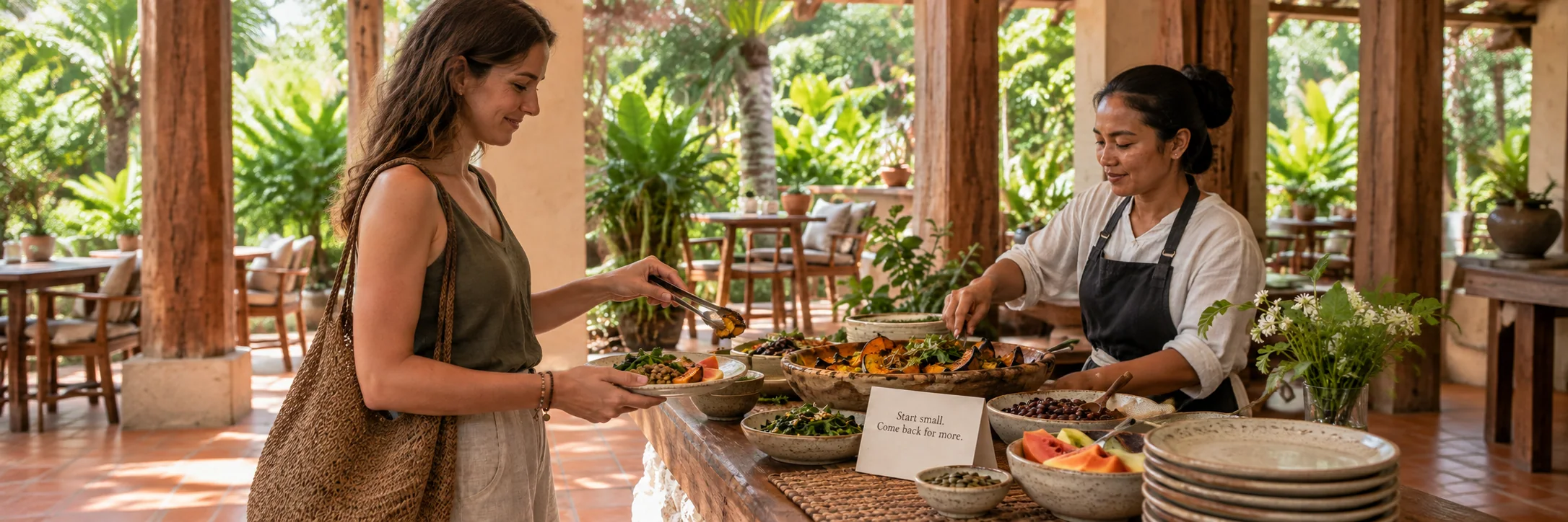 A hotel guest chooses a small serving of local vegetables at a breakfast counter with a gentle invitation to return for more.