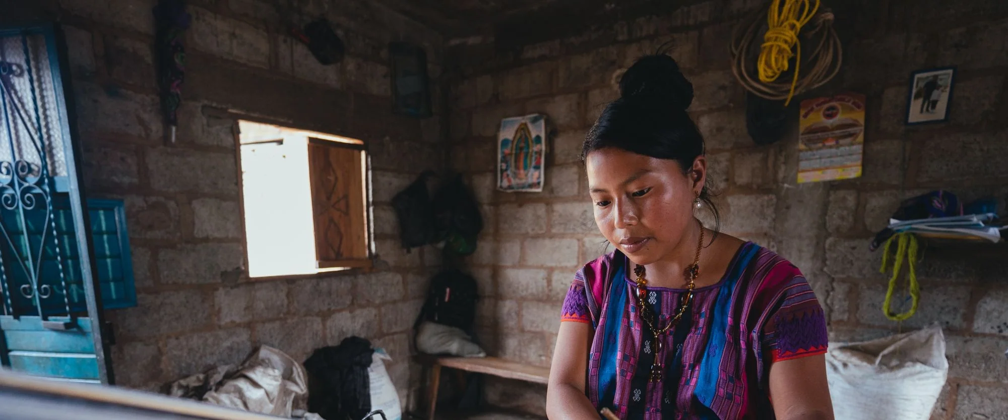 A woman works at a weaving loom in a Mexican artisan workshop.